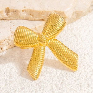 Macro shot of 18K gold plated bow ring with ribbed texture on a beige stone surface