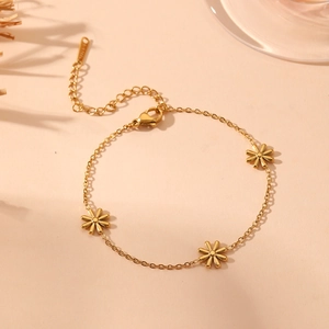 Elegant gold flower tassel bracelet set in stainless steel on a warm peach background