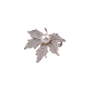 Macro view of maple leaf brooch with sparkling zircons and a central white pearl detail