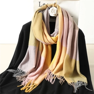 Detail of plaid scarf featuring yellow, pink, and grey knit patterns with soft fringe