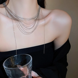 Dettaglio di collane a nappa d'argento a più strati su modella per un look minimalista