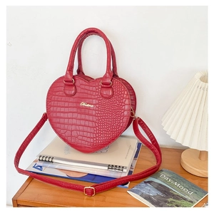 Détail d'un sac à main rouge en forme de cœur à motif crocodile avec logo Buling doré