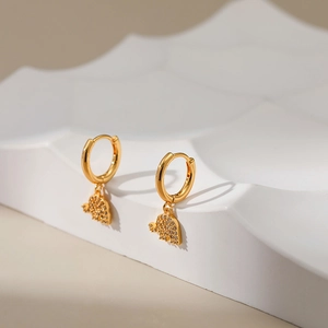 Close-up of gold-plated hoop earrings with micro-dinosaur pendant and zircon inlay