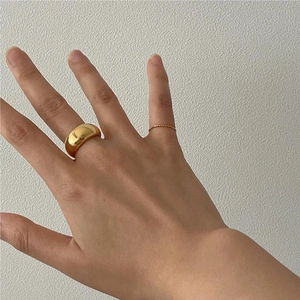 Close-up of a wide polished gold dome ring and slim twisted band worn on fingers
