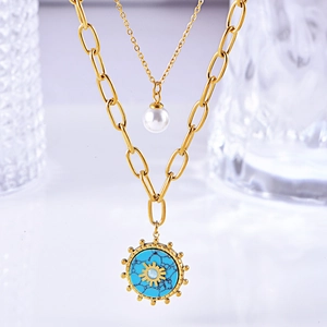 Close-up of golden double-layer necklace featuring a white pearl and turquoise sun pendant