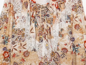 Detail of floral paisley print dress featuring white lace trim and beaded front ties