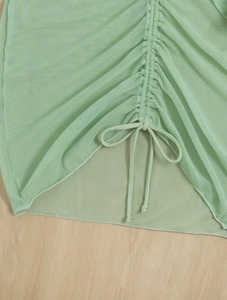 Close-up of light green mesh fabric with ruched drawstring details and soft texture