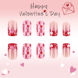 Detail of pink gradient press-on nails with red hearts, XOXO letters and glitter finish