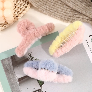 Three plush faux fur hair claw clips in pink and color-block designs on a cozy background