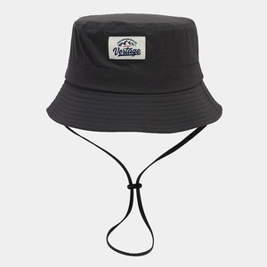 Detail of dark grey sun hat featuring a mountain patch and adjustable chin cord