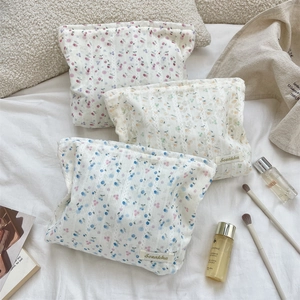 Trois trousses à maquillage matelassées à motifs floraux et étiquette latérale