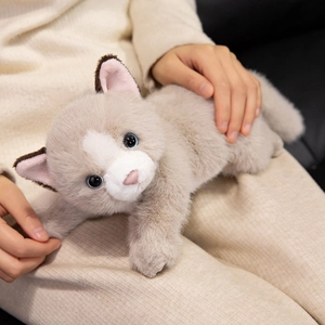 Realistic fluffy Persian cat plush toy with blue eyes in a cozy home setting