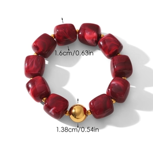 Detailed view of beaded bracelet featuring red marble cubes and a polished gold bead accent