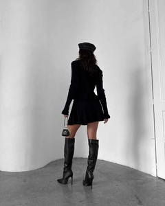 Détail d'un ensemble chic en tricot noir avec jupe plissée et bottes en cuir élégantes