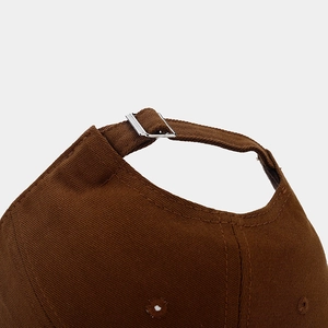 Detailed view of the adjustable metal buckle and brown twill cotton fabric on baseball cap