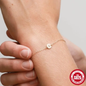 Primer plano de pulsera minimalista de plata S925 dorada con disco grabado de la letra K