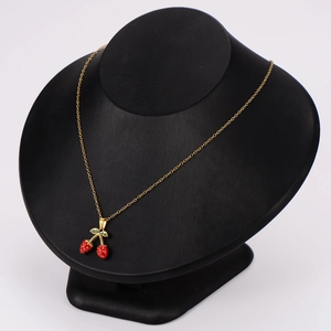 Elegant strawberry pendant necklace with red fruit and green leaves on a gold chain