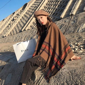 Detail of brown plaid knit shawl with fringe tassels shown in natural outdoor lighting