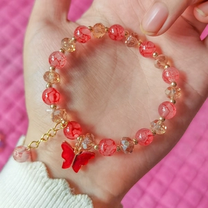 Detail of red beaded bracelet with butterfly pendant and golden extender chain
