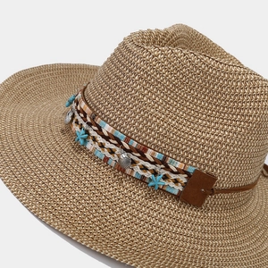 Detail of bohemian sun hat featuring starfish charms and shell pendants on straw