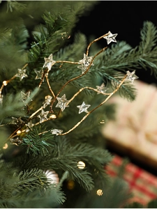 Close-up of golden glitter star ornament on a Christmas tree with warm glowing lights