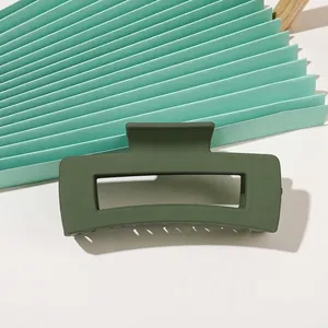 Detail view of dark green matte rectangular hollow hair claw clip on fan background