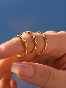 Close-up of three wavy gold stainless steel rings with a polished bamboo texture