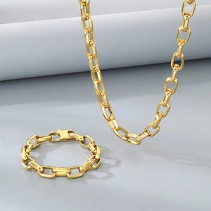 Minimalist golden trapezoid chain link necklace and bracelet jewelry set on grey background