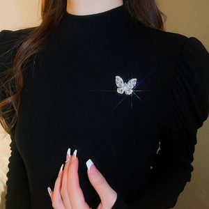Macro shot of silver butterfly brooch with teardrop zircons on a black garment