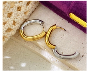 Macro detail of minimalist U-shaped gold and silver mixed-tone stainless steel earrings