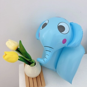 Close-up of inflatable blue elephant swim arm band on a wooden tray with tulips