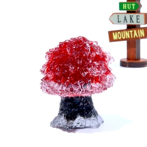 Macro detail of red crystal gemstone tree with black rock base on office desk