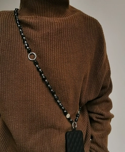 Detail of ethnic style black faux turquoise beaded phone strap crossbody lanyard on model
