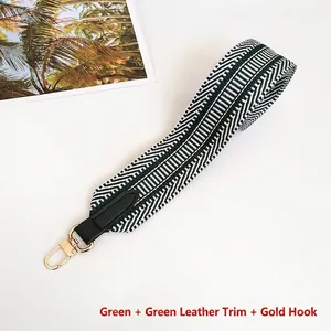 Detail of green and white V-pattern woven wide bag strap with gold metal hooks