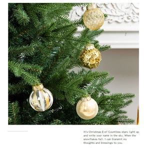 Close-up of golden Christmas balls with glitter and stripes on green tree branches