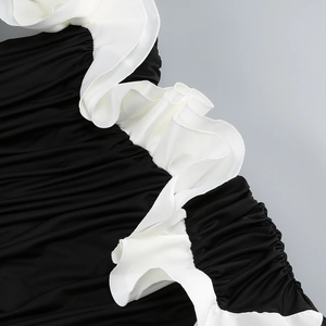 Detail of black pleated fabric with white 3D ruffled trim on elegant evening gown