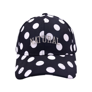 Detailed embroidery of 'NATURAL' text on a black baseball cap with white polka dots