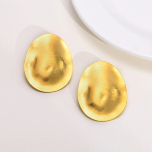 Detail of gold oval earrings with a brushed metallic texture and rippled wavy surface