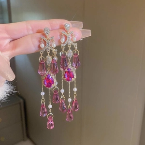Macro detail of long tassel earrings with pink teardrop stones and white pearls