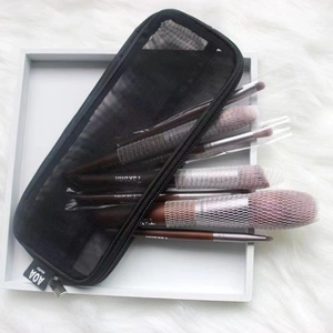 Black nylon mesh makeup brush organizer bag on a white plush rug for travel use