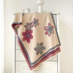 Close-up of bohemian paisley floral pattern on beige winter shawl hanging on drawer