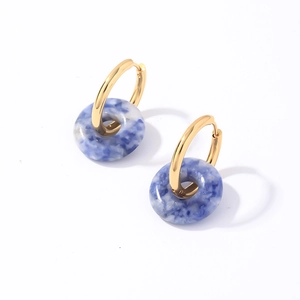 Détail macro de créoles dorées avec pendentifs donuts en pierre marbrée bleue et blanche