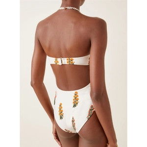 Détail de broderies florales et fermoir métallique d'un monokini blanc ajouré