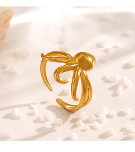 Detail view of golden octopus open ring on natural rock background for beach style