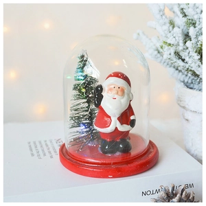 Detail of Christmas glass dome with Santa Claus, mini tree and warm festive light background