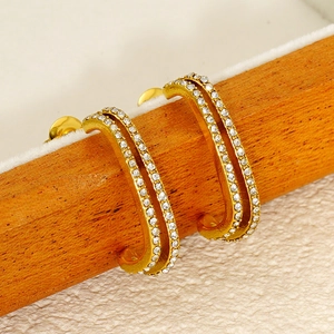 Detailed macro view of gold-plated double-row pavé set C-shaped earrings with crystals