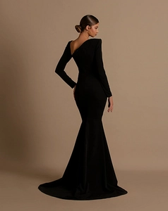 Detail of asymmetrical cutout on the back of a black long sleeve fishtail evening dress