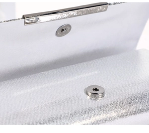 Macro view of silver glitter evening bag with circular magnetic clasp and metal trim
