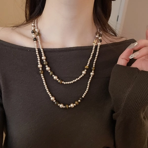 Dettaglio di una collana a due strati con perle bianche e pietre occhio di tigre marroni