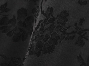 Gros plan sur un tissu jacquard noir avec texture satinée soyeuse et motifs floraux